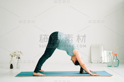 年轻怀孕女孩在运动服装做瑜伽，在工作室做asana Adho mukha shvanasana
