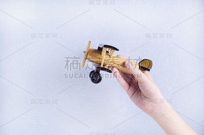 孩子的手拿着一架木制的手工飞机。