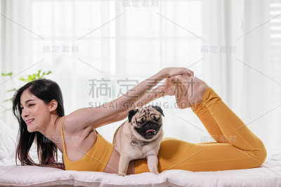 女人练习瑜伽与哈巴狗品种