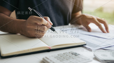 人们在家庭办公室里使用计算器和文件来计算费用。