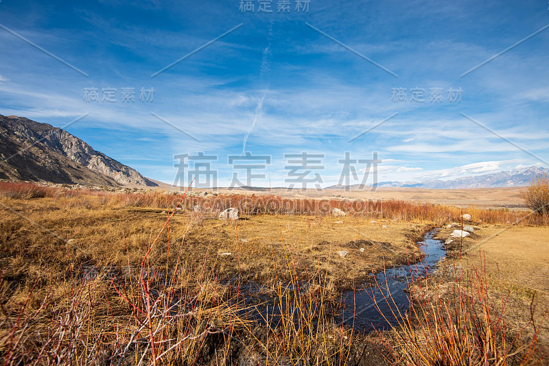 一条小溪流入加州内华达山脉棕色的长满草的山坡