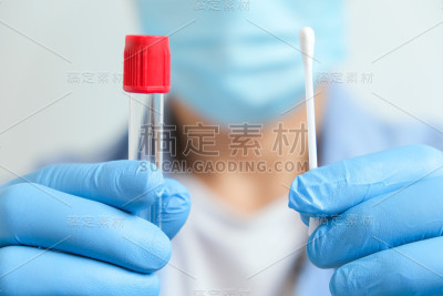 医生手持COVID-19拭子，佩戴蓝色手套和防护口罩，携带试管收集OP NP和检测冠状病毒。