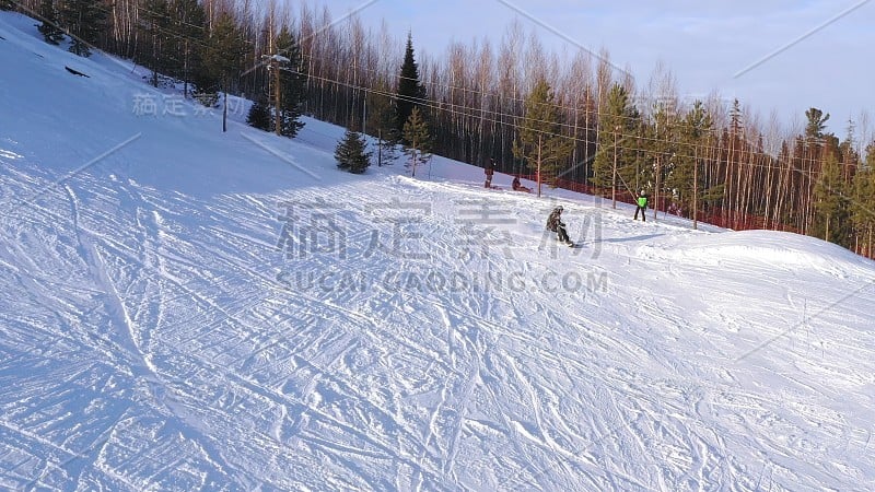 冬季阳光明媚的一天，滑雪者从山顶滑下来的俯视图。单板滑雪的概念