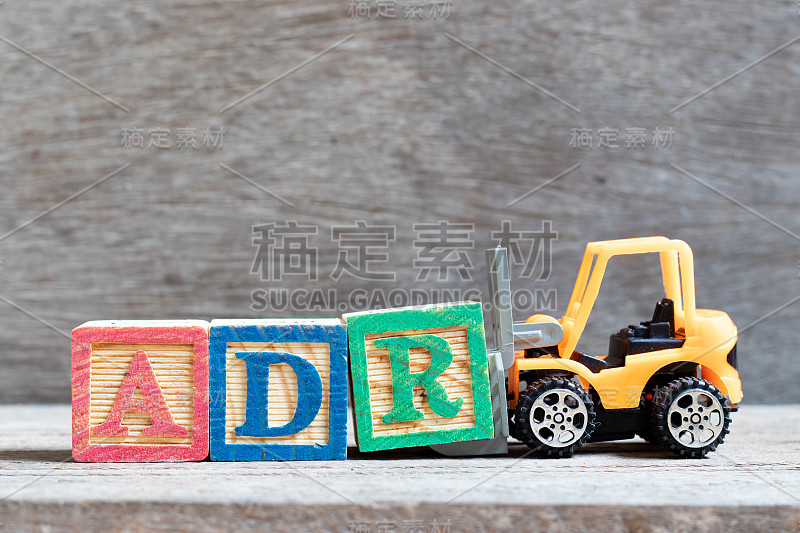 玩具叉车持字母块R来完成ADR(药品不良反应的缩写)字的木质背景