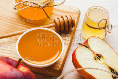 白色木板上放着苹果和蜂蜜