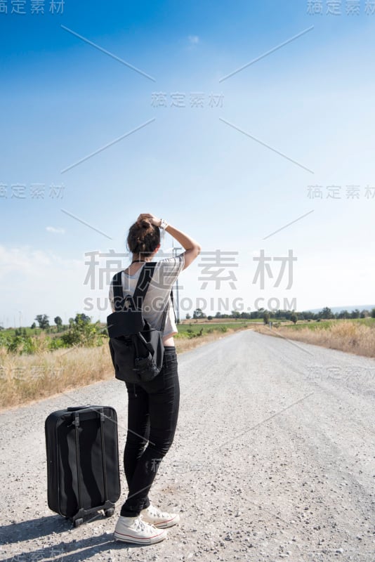 年轻女孩带着包旅行等公共汽车