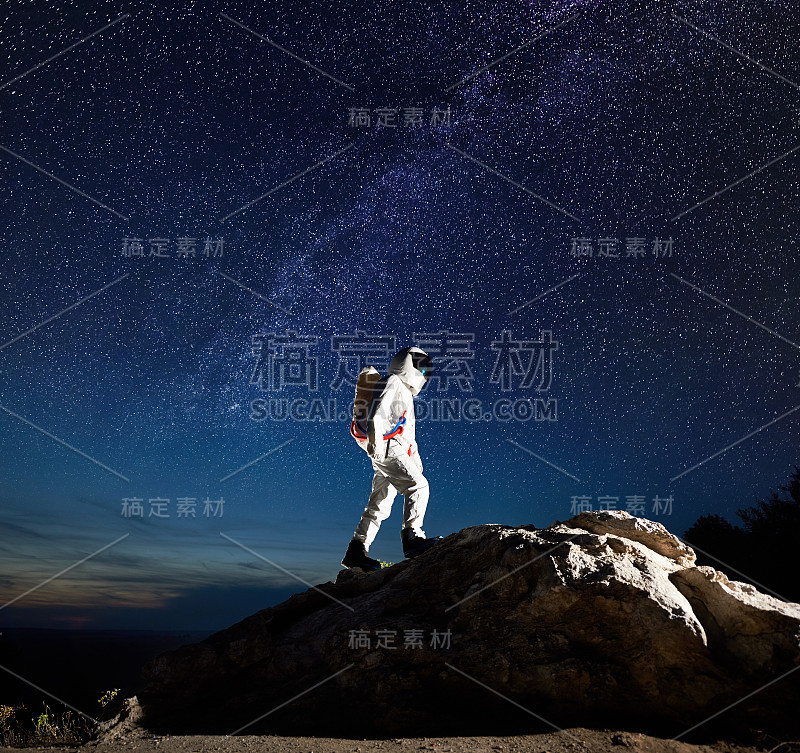 在美丽的星空下，宇航员走上岩石山。