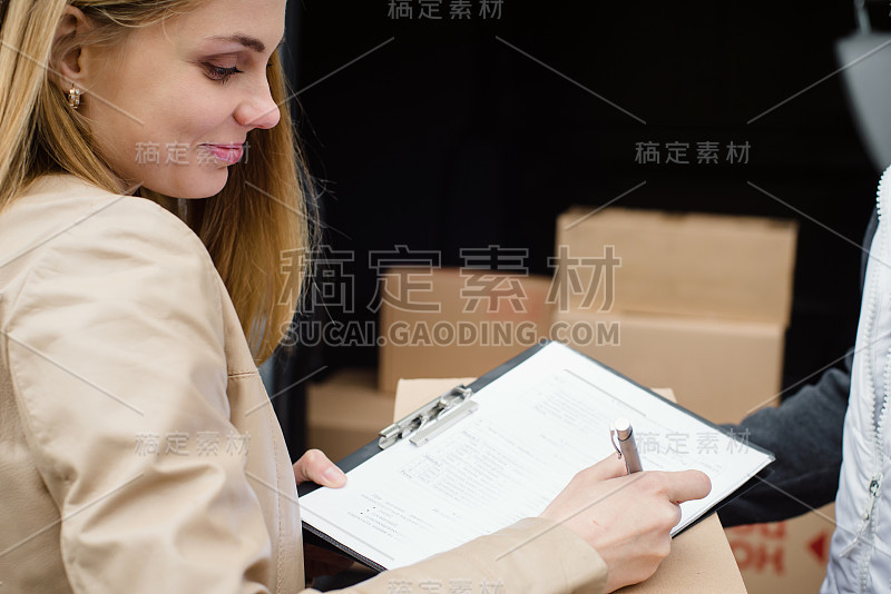 美丽的女人从快递服务接收包裹。