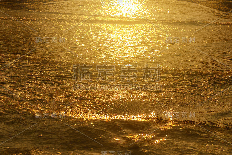 金色的光反射在海浪和沙滩上的夕阳。纯金的语气