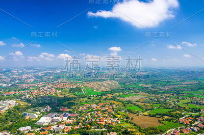 空中顶部全景景观与山谷，绿色的山丘，田野和村庄的共和国圣马力诺郊区与蓝天白云的背景。从圣马力诺要塞观