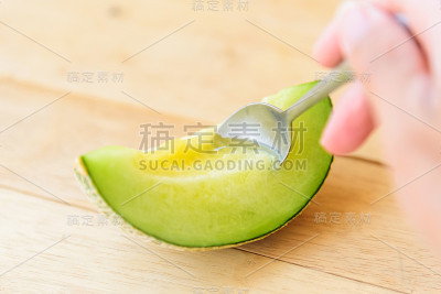 用勺子把新鲜的绿瓜放在木盘上