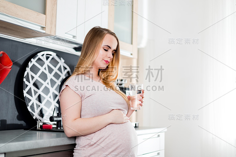 孕妇在厨房饮用淡水，孕期保健概念