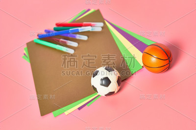 幼儿园粉红色的课桌上放着彩色毡笔、纸和玩具球。Ð’育儿和教育孩子的观念