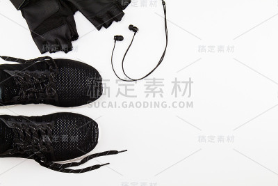 黑色运动鞋，手套和耳机上的白色背景，运动运动的概念