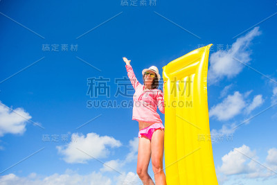 年轻快乐的女人放松与充气床垫在海滩上