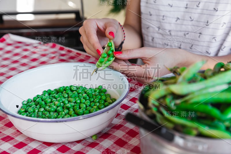 一名妇女正在准备新鲜的有机豌豆，并将其从壳中取出。