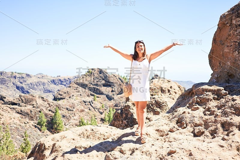 年轻美丽的女人享受暑假在山的景观，快乐地微笑在罗克努布洛山顶在大加那利亚