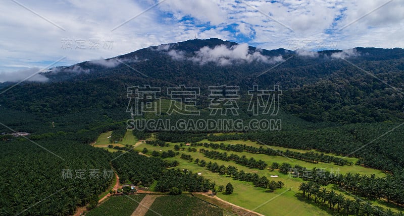 多云晴天的高尔夫球场鸟瞰图，以山为背景。