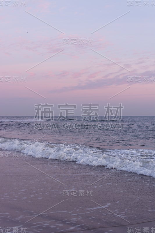 日落时，平静的海浪在海滩上翻滚