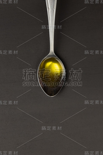 金属勺加特级初榨橄榄油。在黑暗的背景下