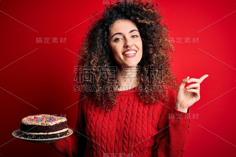 年轻美丽的女人与卷发和穿孔的盘子与生日蛋糕非常幸福的指向与手和手指的一边