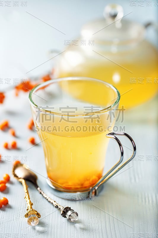 维生素健康沙棘茶小玻璃茶壶与新鲜沙棘生浆果。有选择性的重点