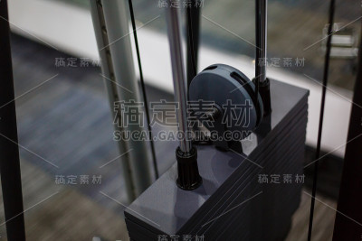 在健身房里，黑色的铁板堆着重量机器，上面有公斤和磅的数字