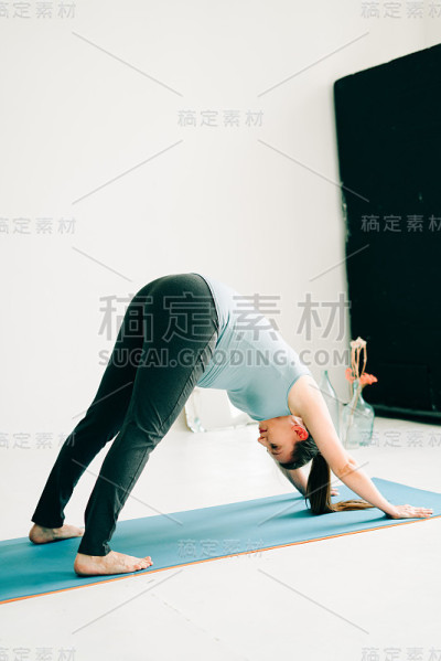 年轻怀孕女孩在运动服装做瑜伽，在工作室做asana Adho mukha shvanasana