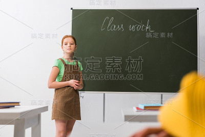有选择地集中心烦意乱的女生站在写有班级作业的黑板旁边