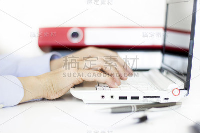 在办公室里用电脑和计算器工作的女商人