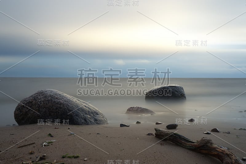 海滩上的夜晚。海湾上的石头。冲浪。