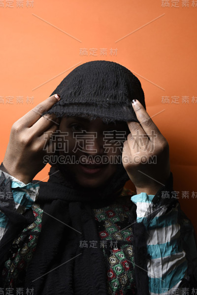 年轻美丽的穆斯林女孩戴着头巾在橙色的背景，女孩在阿拉伯传统阿巴亚