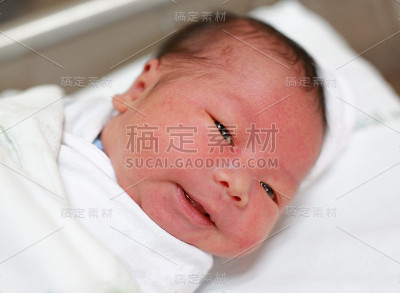 亚洲婴儿的特写脸在毛毯看着相机。