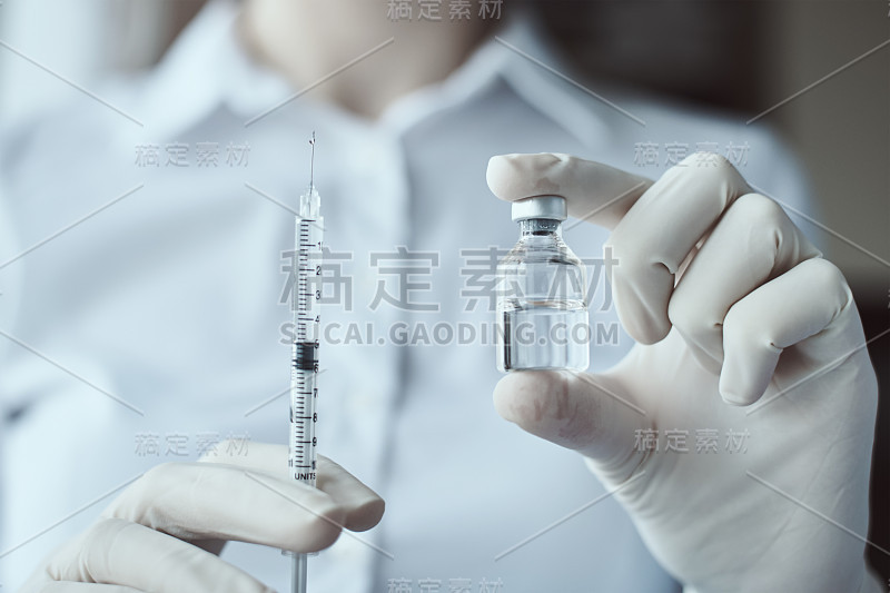 戴手套的妇女拿着注射器和药瓶。保健、医疗和病毒防护概念