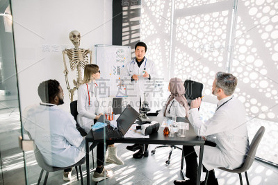 化学实验室的工作人员，医生，科学家在开会。亚洲人解释一个新的项目概念为他的同事。科学发现、医学研究、