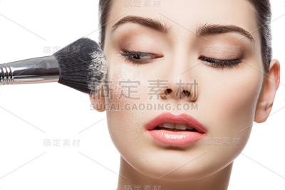 美丽的女孩用刷子涂抹散粉