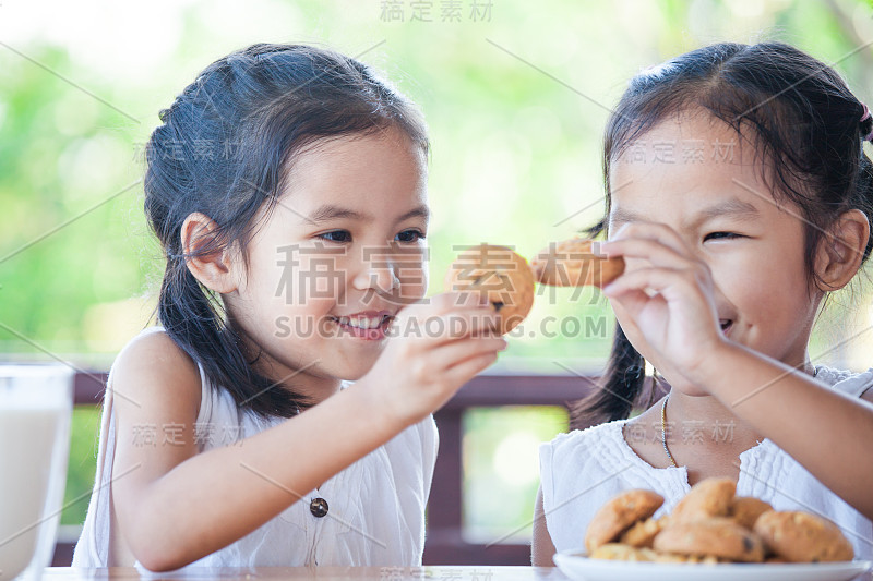 两个可爱的亚洲小女孩快乐地吃着牛奶饼干当早餐