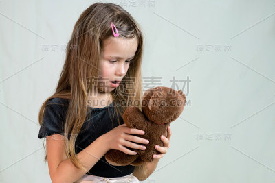 漂亮的小女孩在玩她的玩具熊。
