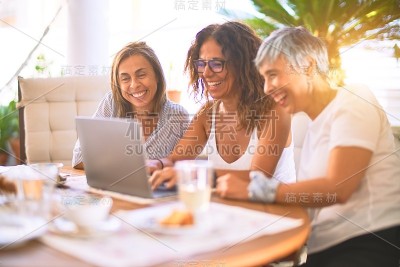 遇见中年妇女吃午饭喝咖啡。在一个阳光明媚的日子里，成熟的朋友们在家里用笔记本电脑，微笑着
