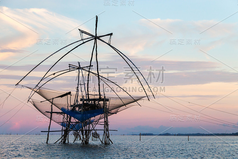 日落天空背景下的方形浸网剪影，泰国帕塔隆Pakpra渔民的生计