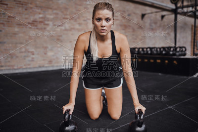 专注的年轻女子在健身房的地板上进行举重锻炼