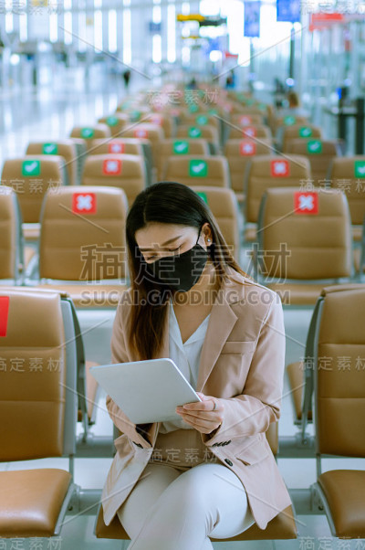 亚洲商务女乘客在机场使用她的数字平板电脑。