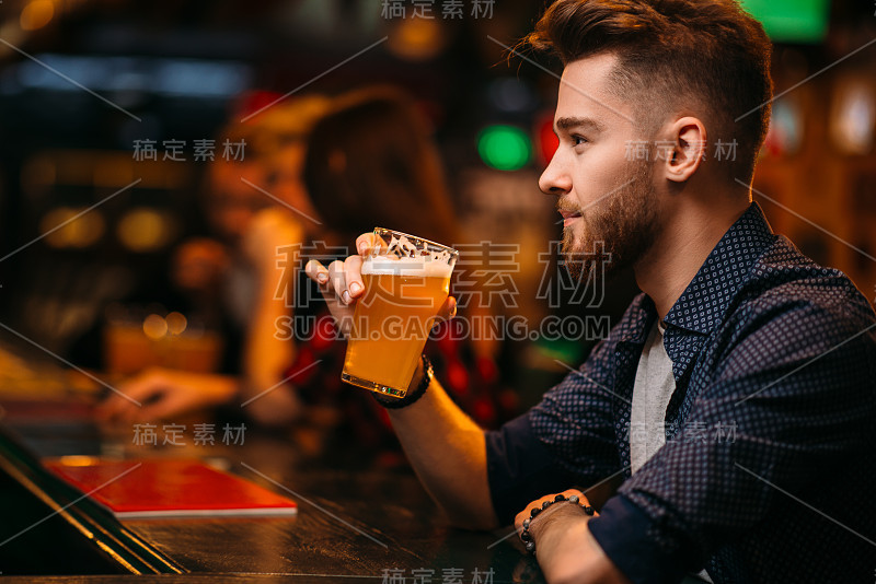 一名男子在一家体育酒吧的吧台边喝啤酒