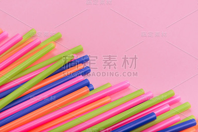 粉红色背景上的彩色小管用于果汁和鸡尾酒。