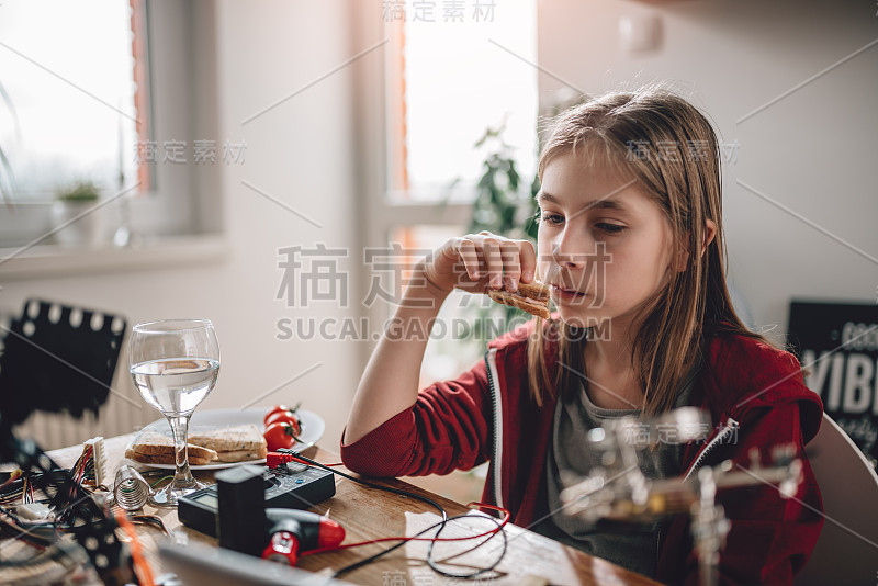 穿着红色连帽衫吃三明治用平板电脑的女孩