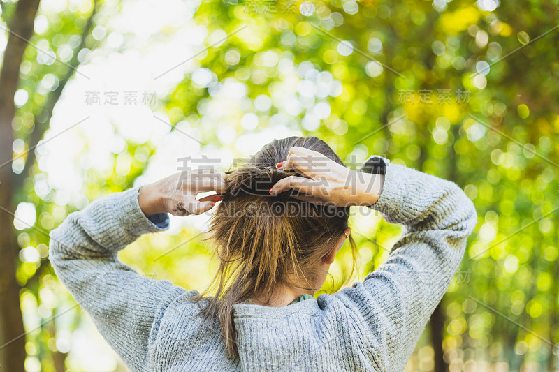 穿着随意的年轻女子在户外整理头发