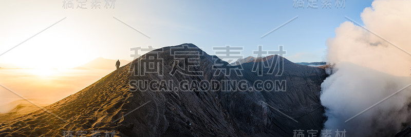 日出时，印度尼西亚Bromo的一名男子走在火山口边缘