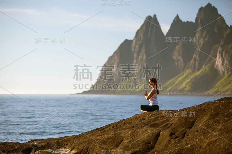 年轻女子在挪威的群山之间练习瑜伽