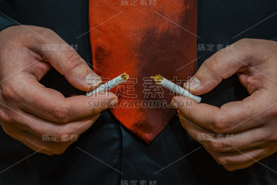 一个男人手里拿着一支断了的香烟。禁止吸烟。