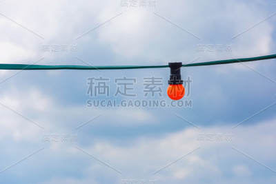蓝色多云的天空中闪烁着橙色的灯泡